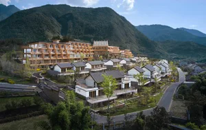 A modern residential village with wooden and glass structures surrounded by mountains.