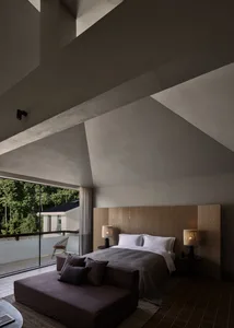 A modern bedroom with a concrete ceiling, wooden headboard, and fabric bedding.