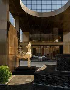 Modern lobby featuring a metal and glass architectural sculpture and a stone fountain.