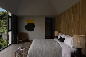 Modern minimalist bedroom featuring wood elements and a large window overlooking a natural landscape.