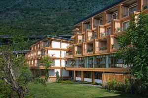 A modern resort hotel with a wooden exterior featuring balconies and glass windows.