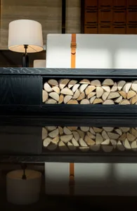 A black chest with a wooden storage compartment, featuring a lamp and a white cushion.