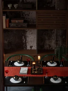 A well-appointed dining table with antique wooden furniture, red tablecloth, and elegant dinnerware.