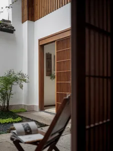 A traditional-style entryway garden with wooden elements and a open door.
