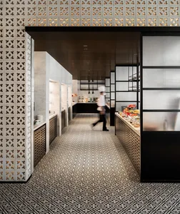 A modern commercial kitchen with tiled floors and walls, metal accents, and a glass partition.
