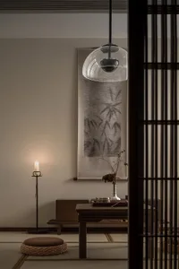 Modern minimalist living room with wooden furniture, candle, and rectangular artwork.