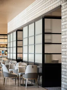 Modern restaurant interior with glass partitions, contemporary furniture, and concrete accents.