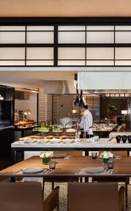 A modern restaurant with a marble counter featuring various food displays and a chef preparing food.