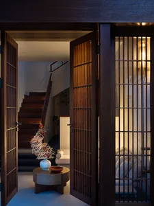 An open wooden entrance hall with a contemporary design, featuring a white vase with a spiral wire arrangement and a minimali