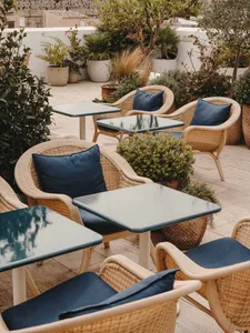 Outdoor seating area of a cafe with wicker chairs and blue cushions.