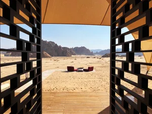 A lounge area in a desert oasis featuring sand, stone, and wooden elements