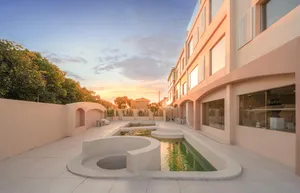Outdoor patio with concrete seating area and small pond at sunset