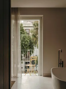 A modern bathroom extension with concrete floors, a window with blinds, and a bathtub.
