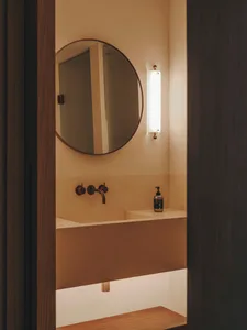 Modern bathroom with concrete countertop and sink, featuring a round mirror and minimalist design.