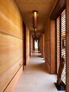 A modern interior hallway featuring wooden paneled walls, white tiled flooring, and minimalist lighting fixtures.