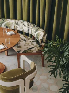 Modern restaurant interior with terrazzo tiles and green curtains.