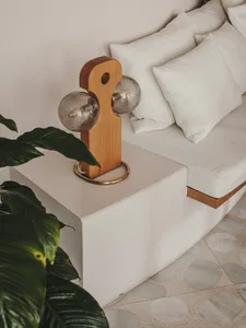 A modern white sofa placed on a concrete floor, accompanied by a unique lamp and a green plant.