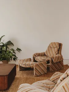 A striped corduroy lounge chair and ottoman in a modern living room setting.