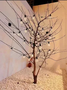 A decorative tree adorned with light bulbs against a white wall background