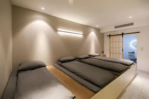 A minimalist bedroom with grey beds and wooden accents.
