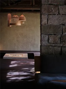 Modern minimalist living room featuring wood flooring, stone walls, and metal accents.