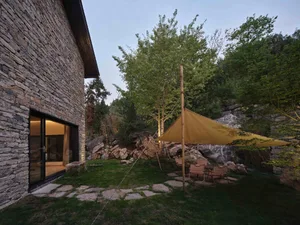 Outdoor patio with modern furniture, rock walls, and a tent setup