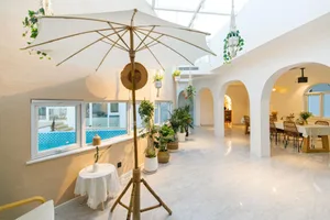 A modern living room with white marble floors and various potted plants.
