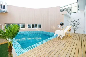 A modern residential space featuring a pool with blue-tiled walls and a wooden deck.