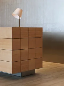 A modern wooden sideboard with a table lamp on top, set against a minimalist background.