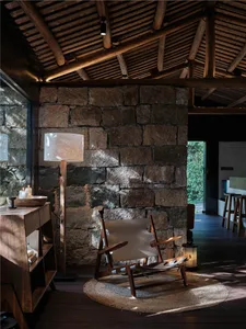 A rustic living room featuring wooden furniture and a stone wall