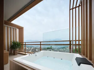 A modern bathroom featuring a glass hot tub with a view of a town and mountains.