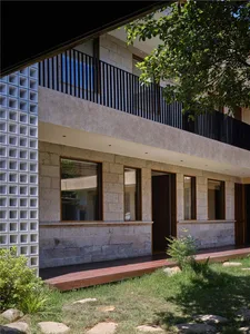 Modern residential house exterior featuring stone, concrete, and glass materials.