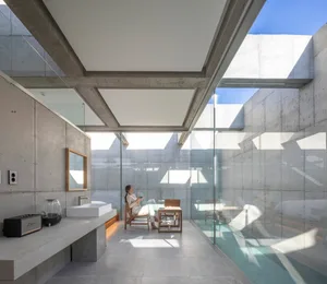 A modern residential kitchen featuring concrete walls and glass elements.