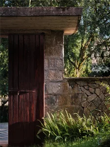 A rustic wooden door with a stone frame surrounded by lush greenery and stone walls.