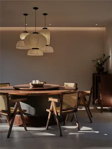 A modern dining room with a round wooden table and four chairs, adorned with white paper lanterns hanging from the ceiling.