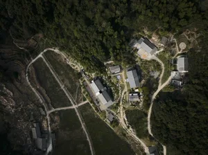 An aerial view of a village with lush greenery and winding roads.