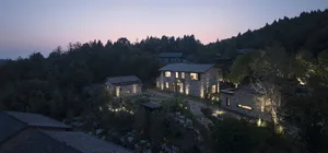 A stone house illuminated at dusk with lights highlighting the exterior.