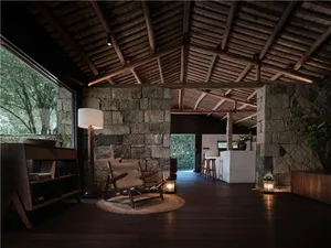 Industrial living room featuring stone walls, mortar, and concrete floor.