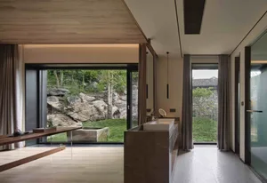 Modern minimalist bathroom featuring concrete materials and large windows overlooking greenery.