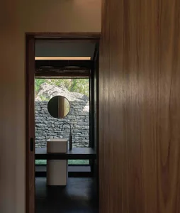 Modern bathroom with stone walls and a wooden vanity.