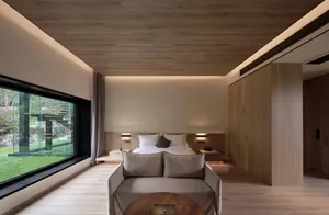 Bedroom with a modern design featuring wooden furniture and a large window overlooking a natural landscape.