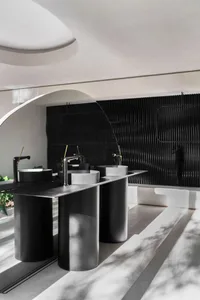A modern, industrial-style bathroom with metallic elements and concrete sinks.