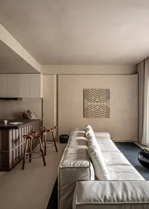 Modern living room with white sofa and geometric pattern on wall.