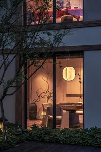 寧靜的夜晚場景，展現一間客廳搭配柔和暖光、木質家具與植栽。
