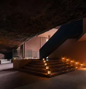 An industrial-style staircase with metal railings and steps illuminated by lanterns under a textured ceiling.