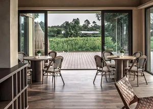 A modern minimalist cafe interior with wooden tables and chairs, overlooking a sunflower field.