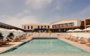A modern resort architecture featuring a minimalist interior with concrete and wooden elements.