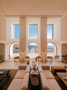 Modern hotel lobby featuring sleek, minimalist design with concrete floors, glass walls, and natural light.