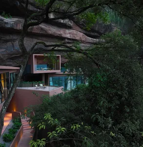 A modern house blending concrete and glass materials surrounded by nature.