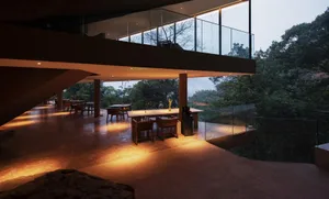 Modern restaurant with glass balcony overlooking lush forest.